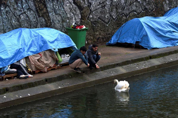 Begunci, ki v Parizu životarijo pod milim nebom ob Seni. FOTO: Reuters