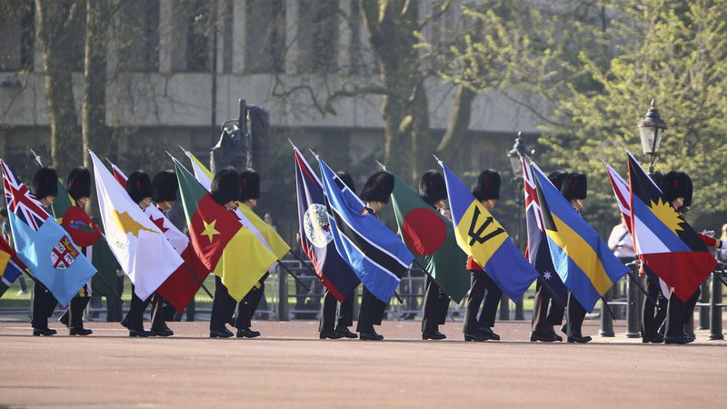 Fotografija: Častna straža pred Buckinghamsko palačo nosi zastave držav članic Skupnosti narodov. FOTO: Gareth Fuller/PA via AP