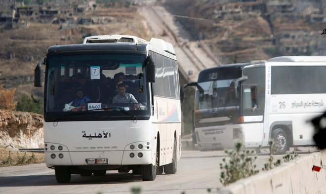 Uporniki in njihove družine zapuščajo mesto Rastan. FOTO: Omar Sanadiki/Reuters