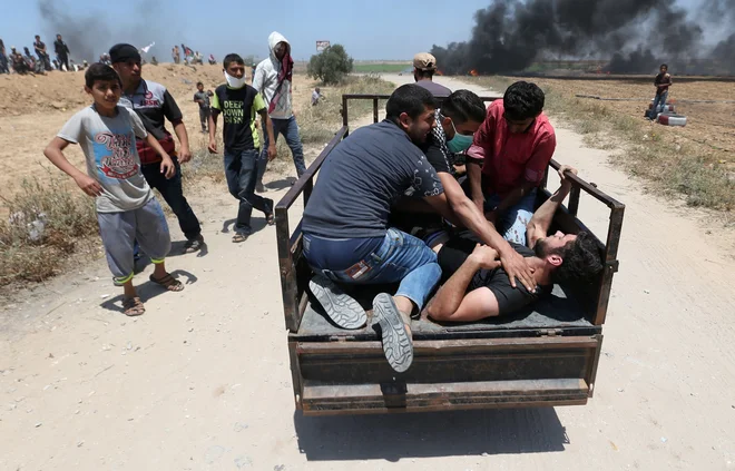 Ranjenec v spopadih na meji med Gazo in Izraelom. FOTO: Reuters/Ibrahim Abu Mustafa