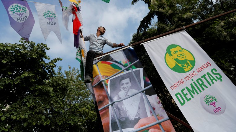 Fotografija: Podporniki kurdske Demokratične ljudske stranke obešajo plakate zaprtega sovoditelja stranke Selahattina Demirtaşa. FOTO: Reuters