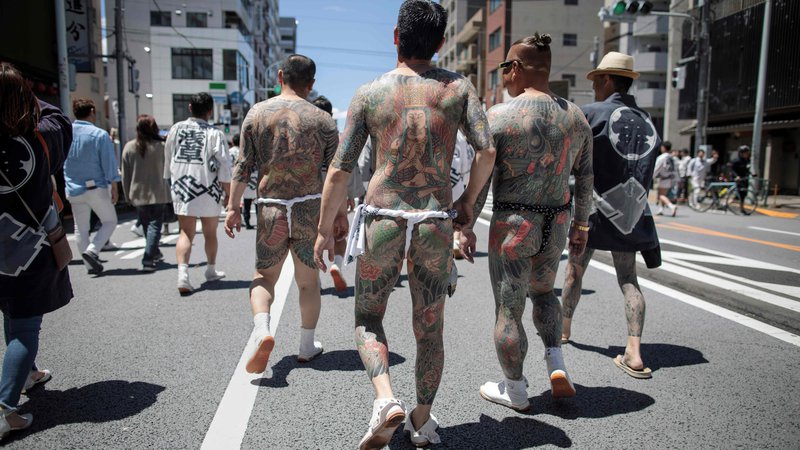Fotografija: Jakuze s svojimi tradicionalnimi japonskimi tetovažami (irezumi), se sprehajajo po tokijskem okrožju Asakusa med letnim festivalom Sanja Matsuri. Tridnevni festival, ki ga obišče dva milijona Japoncev, je posvečen praznovanju treh ustanoviteljev templja Sensoji. FOTO: Behrouz Mehri/AFP