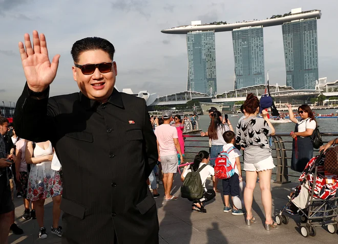 Howard X, Avstralec kitajskega rodu, ki je zelo podoben Kim Džong Unu, v parku Merlion v Singapurju pozdravlja mimoidoče. FOTO: Reuters