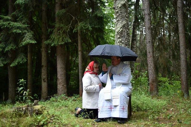 Katoliški duhovnik posluša spoved ene od vernic med letnim praznovanjem praznika &raquo;Ikona matere večne pomoči&laquo; v gozdu blizu vasi Dubok, približno 180 kilometrov severozahodno od Minska. FOTO: Sergej Gapon/AFP
