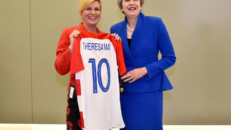 Fotografija: Pred polfinalnim dvobojem na SP med Hrvaško in Anglijo je hrvaška predsednica Kolinda Grabar-Kitarović (levo) britanski premierki Theresi May na vrhu Nata v Bruslju podarila hrvaški dres s številko 10. FOTO: AFP