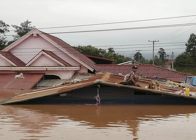 A villager takes refuge on a rooftop above flood waters from a collapsed dam in the Attapeu district of southeastern Laos, Tuesday, July 24, 2018. The official Lao news agency KPL reported Tuesday that the Xepian-Xe Nam Noy hydropower dam in Attapeu province collapsed Monday evening, releasing large amounts of water that swept away houses and made more than 6,600 people homeless. (Attapeu Today via AP)
