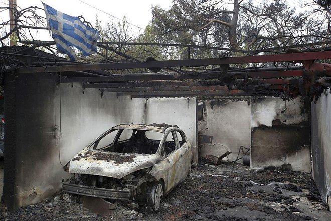 V požaru poškodovana grška zastava kot simbol grške ognjene tragedije. FOTO: AP