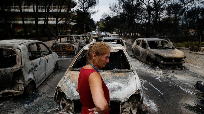 Fotografija: Lokalna prebivalka si v Mati ogleduje uničene avtomobile na eni izmed ulic. FOTO: Costas Baltas/Reuters