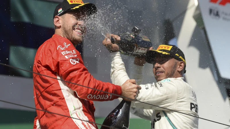 Fotografija: Lewis Hamilton (desno) je po včerajšnji zmagi na Hungaroringu takole s šampanjcem poškropil drugouvrščenega Sebastiana Vettla. FOTO: AP