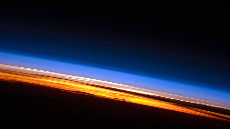 Fotografija: Na tej fotografiji sončnega zahoda, posnetega z Mednarodne vesoljske postaje, so jasno vidne tri plasti atmosfere: troposfera se sveti oranžno, stratosfera, kjer se najaha ozon, je roza, višje plasti so modrikaste. FOTO: Nasa