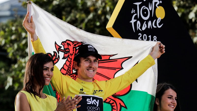 Fotografija: Tour de France 2018 winner Great Britain's Geraint Thomas (C) holds a Welsh flag as he celebrates his overall leader yellow jersey on the podium after the 21st and last stage of the 105th edition of the Tour de France cycling race between Houilles and Paris Champs-Elysees, on July 29, 2018. / AFP PHOTO / Thomas SAMSON Foto Thomas Samson Afp