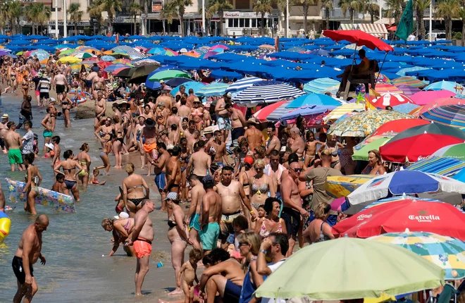 Turisti v Španiji med vročino iščejo ohladitev v morju. FOTO: Reuters