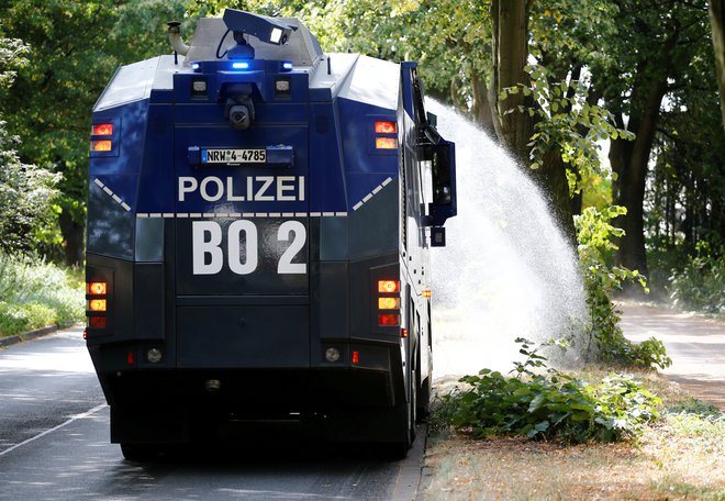Nemški policisti z vodnim topom zalivajo drevesa. FOTO: Wolfgang Rattay/Reuters