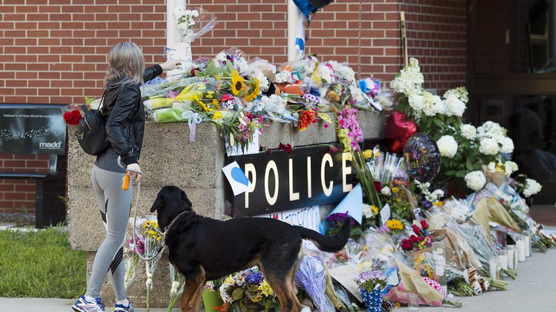 Fotografija: Cvetje, položeno na spomeniku pred policijsko postajo. Med štirimi ubitimi sta bila dva policista. FOTO: Andrew Vaughan/AP