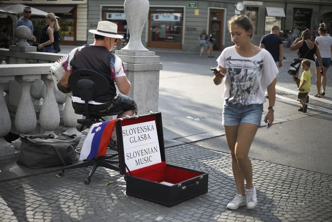 Harmonikar Marko Hočevar je že inventar na Tromostovju. FOTO Blaž Samec