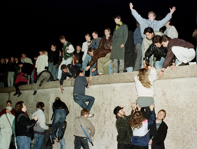 Berlinski zid je padel 9. novembra 1989. Na sliki so prebivalci vzhodnega dela Berlina, ki pri Brandenburških vratih proslavljajo odprtje več kot 28 let zaprte meje. FOTO: Str Old Reuters