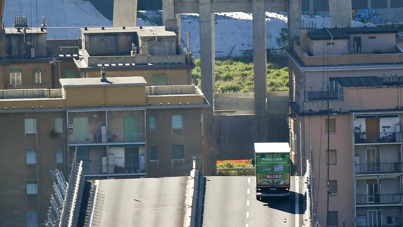 Fotografija: A truck is blocked at the end of the collapsed Morandi highway bridge in Genoa, northern Italy, Wednesday, Aug. 15, 2018. A bridge on a main highway linking Italy with France collapsed in the Italian port city of Genoa during a sudden, violent storm, sending vehicles plunging 90 meters (nearly 300 feet) into a heap of rubble below. (Luca Zennaro/ANSA via AP)