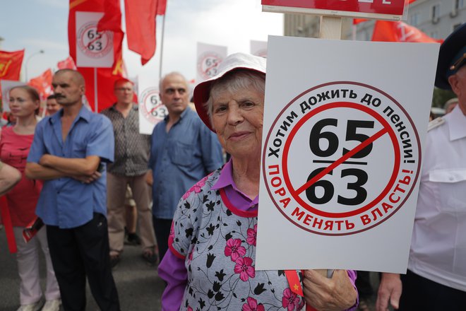 Starejša ženska drži plakat z napisom »Želim se upokojiti«. FOTO: AP