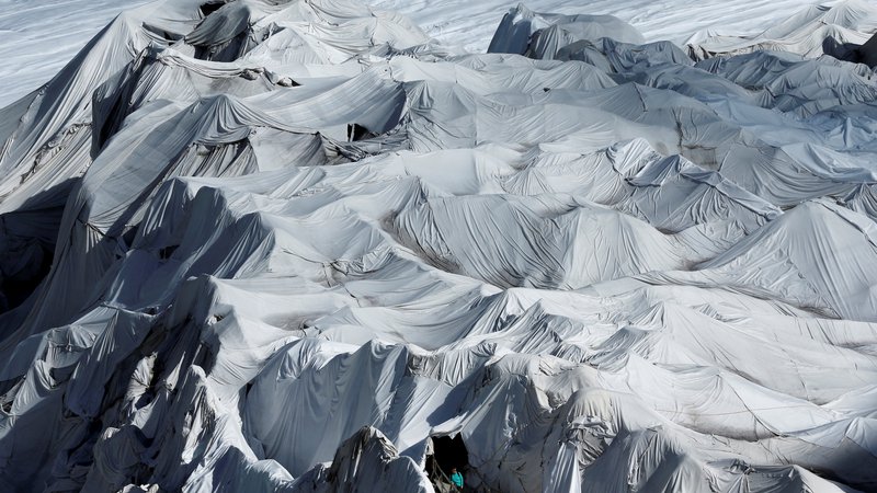 Fotografija: Ženska pozira na vhodu v ledeno jamo na švicarskem ledeniku Rhone. FOTO: Denis Balibouse/Reuters