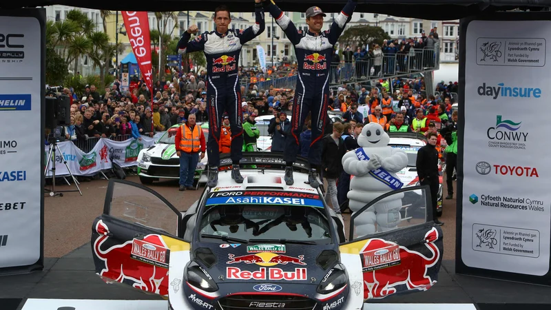 Fotografija: Sebastien Ogier in njegov sovoznik Julien Ingrassia sta se takole na strehi svojega forda veselila četrte letošnje zmage v svetovnem prvenstvu. FOTO: Geoff Caddick/AFP