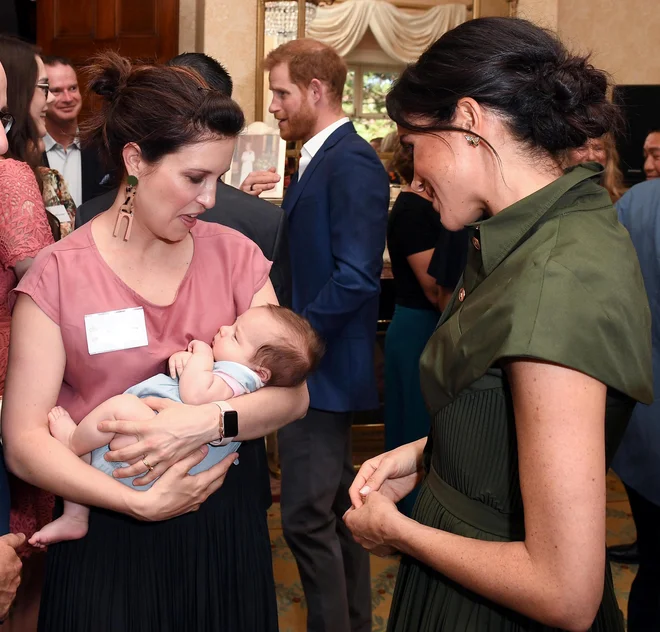 Meghan Markle na sprejemu v Sydneyju med klepetom z avstralsko pevko Missy Higgins, ki je s seboj prinesla devet tednov staro dojenčico Lunar. FOTO: Andrew Parsons/Reuters
