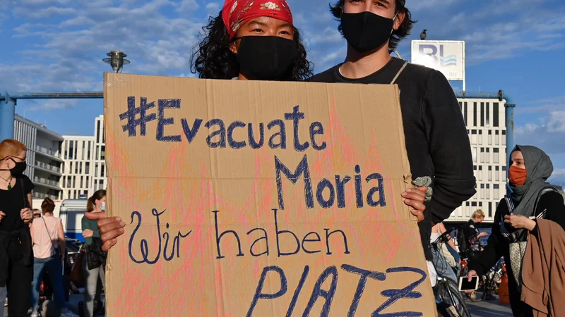 Fotografija: »Evakuirajte Morio. Pri nas je dovolj prostora!« piše na plakatu protestnikov v Berlinu, ki so se včeraj zavzeli za sprejem beguncev in migrantov z Lezbosa. FOTO: John Macdougall/AFP