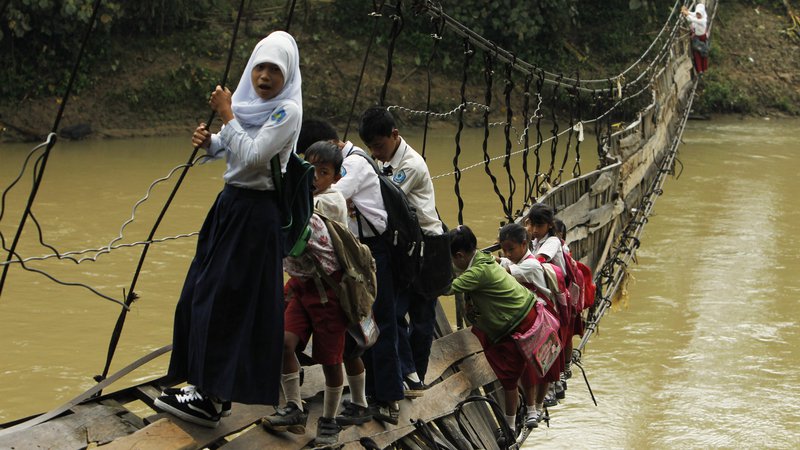 Fotografija:  Otroci morajo po uničenem visečem mostu, ki je edina možna pot do šole v odročni indonezijski provinci. Foto Beawiharta Beawiharta Reuters
