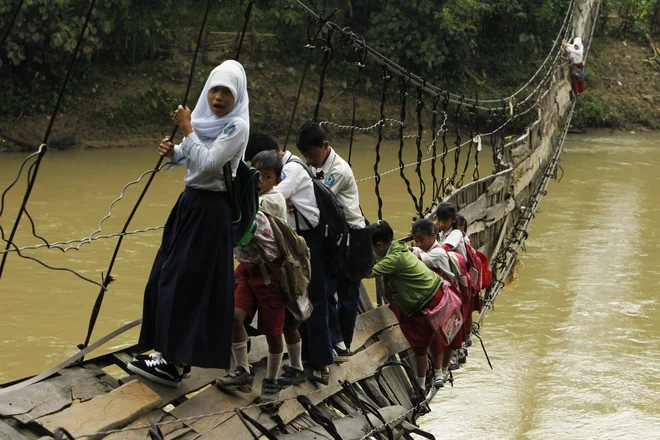  Otroci morajo po uničenem visečem mostu, ki je edina možna pot do šole v odročni indonezijski provinci. Foto Beawiharta Beawiharta Reuters