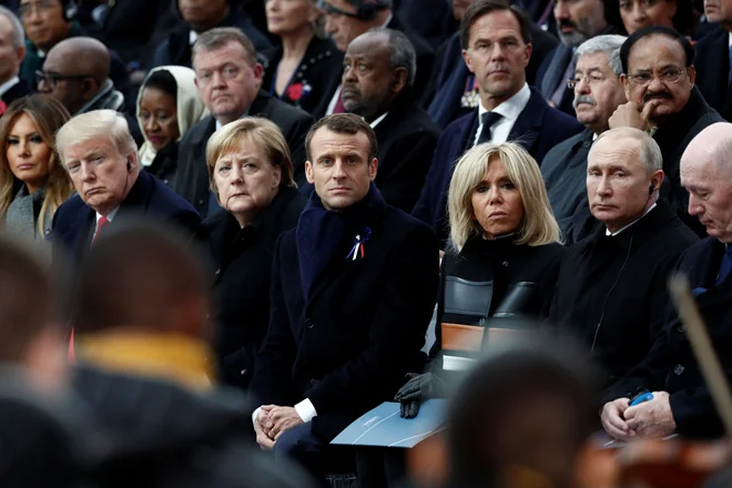 V prvi vrsti so ob Emmanuelu in Brigitte Macron sedeli Donald Trump v obvezni rdeči kravati, kanclerka Angela Merkel, Vladimir Putin ... FOTO: Reuters