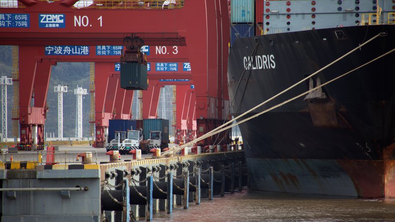 Fotografija: Tovornjaki dostavljajo kontejnerje, ki jih bodo naložili na ladjo v pristnišču Zhoushan na Kitajskem.
Foto Reuters