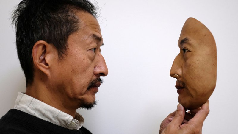 Fotografija: Predsednik REAL-f Co. Osamu Kitagawa drži superrealistično masko obraza v tovarni v japonskem Otsu. Foto Kwiyeon Ha Reuters