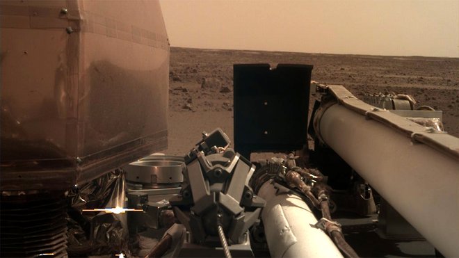Kamera, ki bo skrbela za pravilno postavitev znanstvenih instrumentov na robotski roki landerja, je posnela fotografijo območja pristanka. Na posnetku je še viden prozoren filter, da so kamero zaščitili proti prahu, ki se je dvignil ob pristanku. FOTO: NASA/JPL-Caltech 