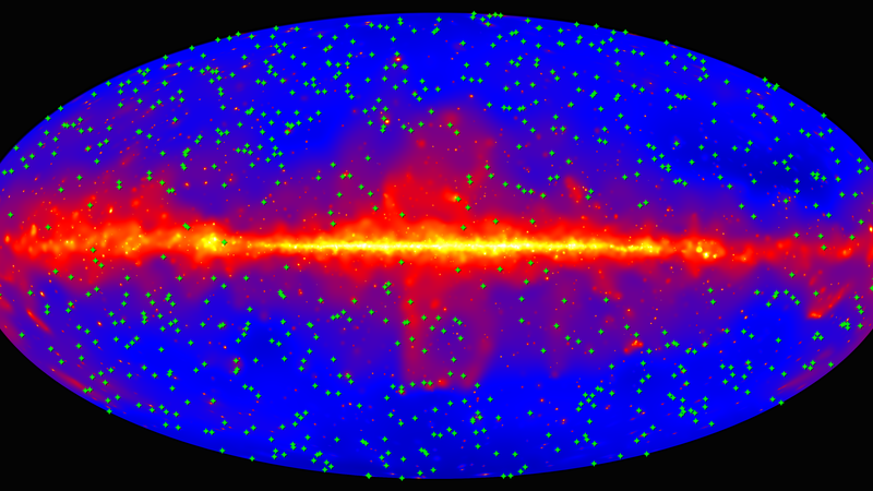 Fotografija: Karta celotnega neba prikazuje položaje 739 blazarjev (zeleni križci), ki so jih v raziskavi Fermi LAT uporabili za merjenje zunajgalaktične svetlobe ozadja. Ozadje (modra) prikazuje nebo, kot ga je v 9 letih opazovanj videl Fermi LAT v visoko-energijski gama svetlobi. Ravnina naše Galaksije poteka vodoravno po sredini slike. Foto Vir: Nasa/doe/fermi Lat Collaboration.