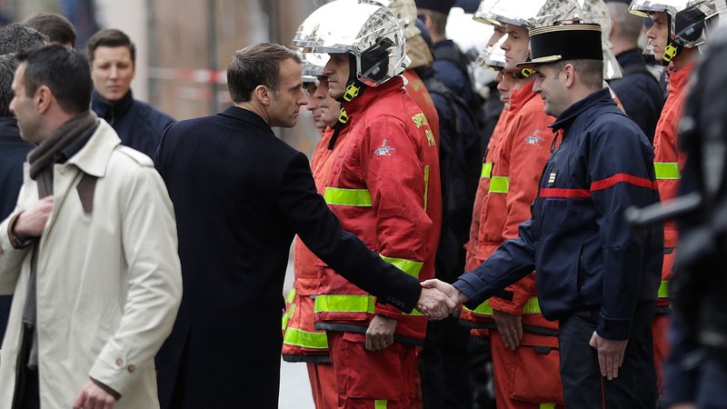 Fotografija: Francoski predsednik pozdravlja pripadnike gasilskih enot, ki so posredovali pri gašenju požarov na desetine požarov v središču Pariza. FOTO: Geoffroy VAN DER HASSELT / AFP