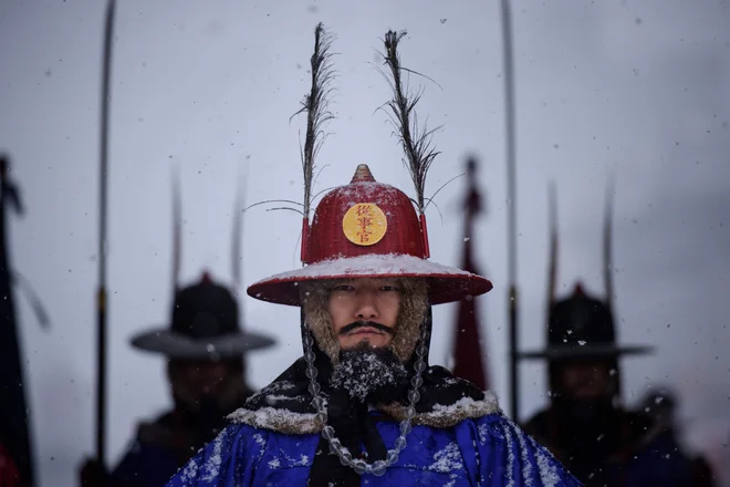 Portret južnokorejskih čuvajev palače Gyeongbokgung v Seulu med snežnim metežem. FOTO: Ed Jones/AFP
