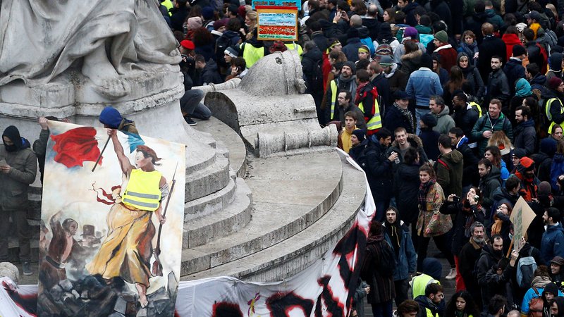 Fotografija: A protester holds a drawing featuring a Marianne with a yellow vest at the Place de la Republique during a national day of protest by the 
