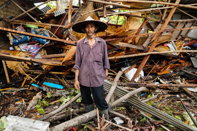 Moški stoji pred svojim uničenim domovanjem. FOTO: Jorge Silva/Reuters