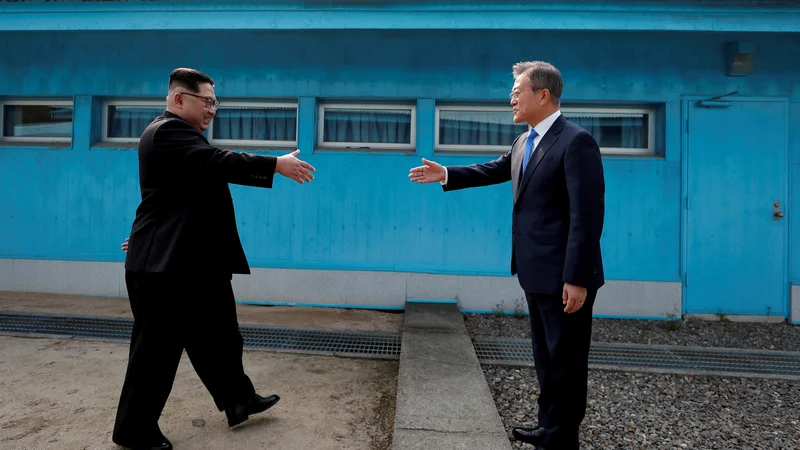 Fotografija: Zgodovinsko rokovanje severnokorejskega voditelja Kim Džong Una in južnokorejskega predsednika Mun Dže Ina znotraj demilitariziranega območja med obema Korejama. FOTO: Reuters