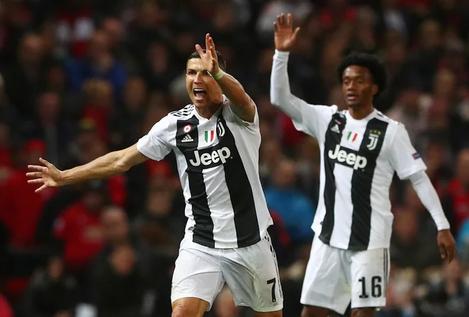 Juan Cuadrado (na fotografiji s soigralcem pri Juventusu Cristianom Ronaldom) bo zaradi bolniške odsotnosti morda manjkal tudi v osmini finala lige prvakov. FOTO: Hannah Mckay/Reuters