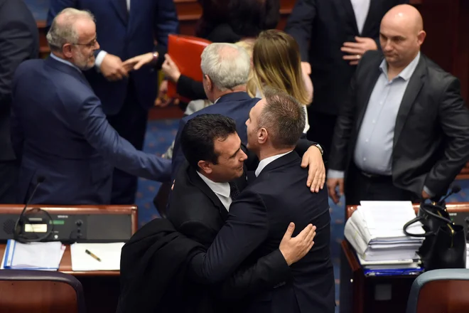 Makedonski premier Zoran Zaev v objemu enega od poslancev sobranja proslavlja zgodovinsko potrditev ustavnih sprememb. Foto AFP