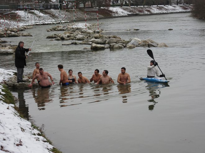Plavalci so se zvrstili v ravni vrsti, predsednik Kajak kanu kluba Nivo Celje Dušan Konda (skrajno levo) je z mečem dal znak za začetek plavanja za križ. FOTO: Špela Kuralt/Delo