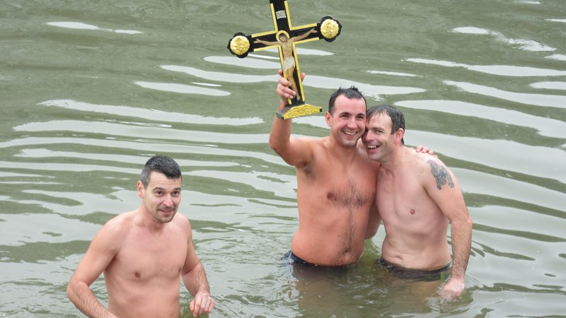 Fotografija: Zmagovalec plavanja za križ v Savinji je letos Ljubiša Šolajić (v sredini s križem), desno je David Tepić, levo podpredsednik Zveze srbske diaspore Slovenije Igor Mitić. FOTO: Špela Kuralt/Delo