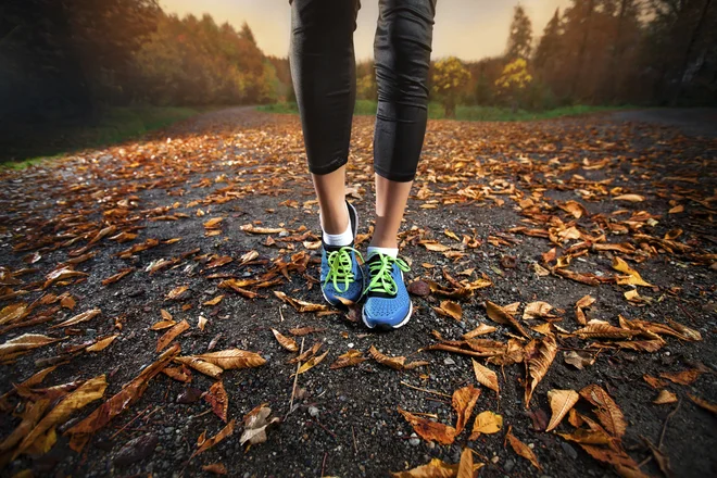 young woman running in the early evening autumn leaves