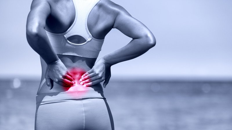 Fotografija: 34943050 - back pain. athletic running woman with back injury in sportswear rubbing touching lower back muscles standing on road outside.