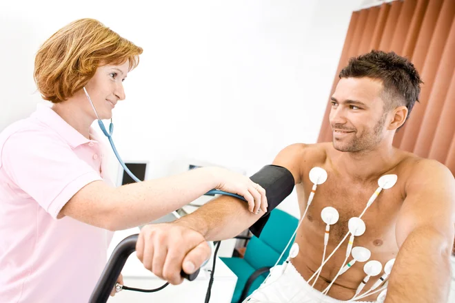 Nurse makes the patient ready for medical EKG test. Real people, real locacion, not a staged photo with models.