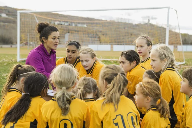 Soccer coach discussing strategy with players on field