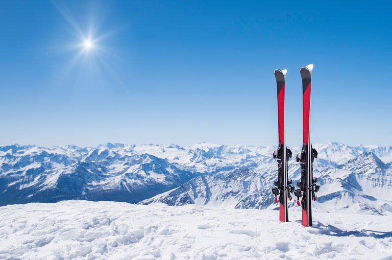 Fotografija: Pair of skis in snow with copy space. Red skis standing in snow with winter mountains in background. Winter holiday vacation and skiing concept.