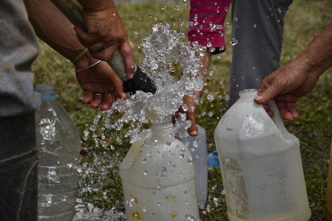 Venezuelci se morajo znajti da si priskrbijo pitno vodo. Foto Yuri Cortez Afp