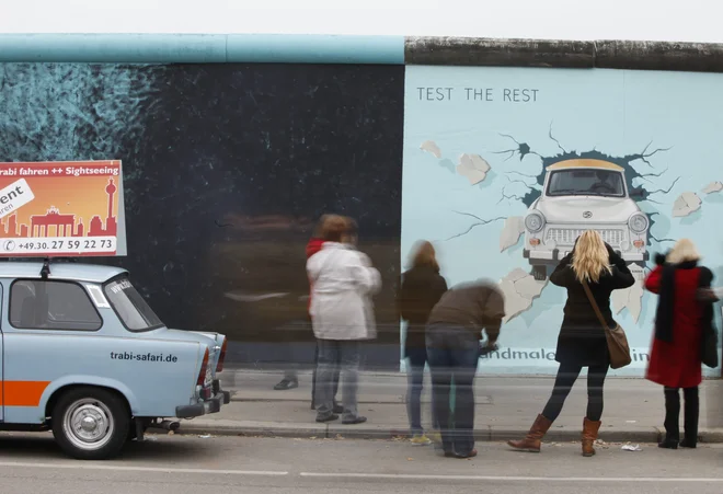 People take pictures of a mural of an East German Trabant car painted at a restored segment of the East Side Gallery, the largest remaining part of the former Berlin Wall, in Berlin November 8, 2009.  REUTERS/Thomas Peter  (GERMANY POLITICS ANNIVERSARY ENTERTAINMENT)