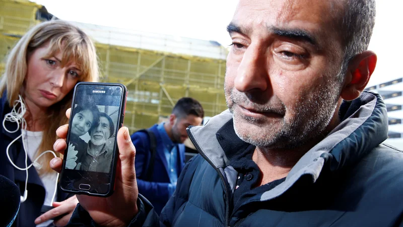Fotografija: Omar Nabi (na fotografiji) novinarjem govori o svojem očetu (na sliki na telefonu) Daoudu, ki je bil prva identificirana žrtev napadov. FOTO: Edgar Su/Reuters